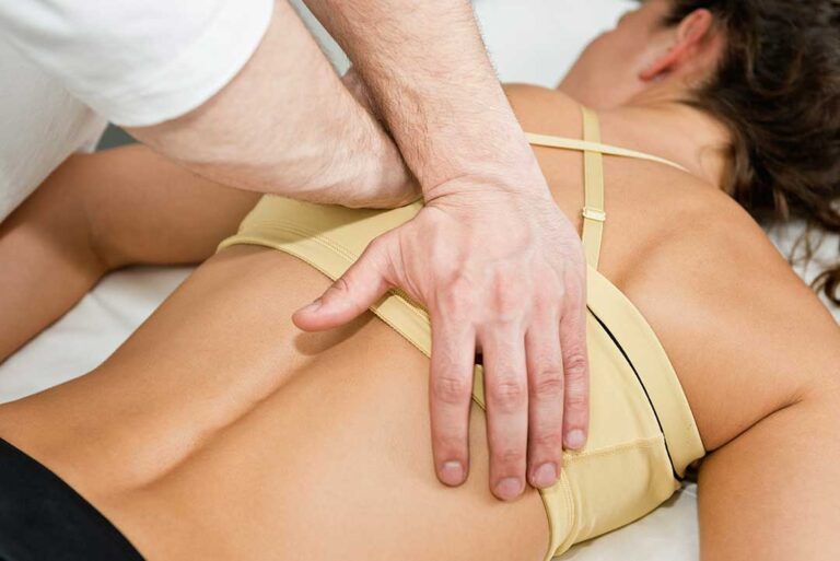 A chiropractor gently adjusting a patient's upper back in a comfortable clinic setting.