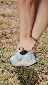 Person walking while a clinician observes foot placement, pelvic position, and spinal posture from the side.